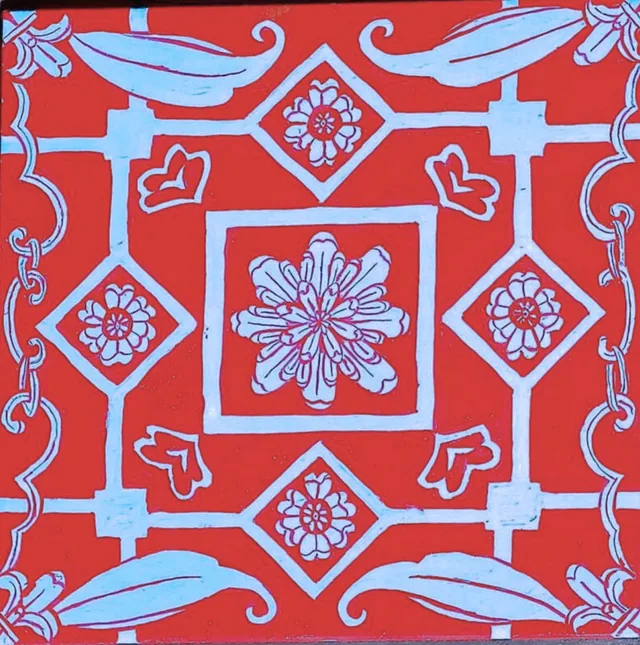 A 20 by 20 centimetre tile hand-painted with a red and blue floral pattern.